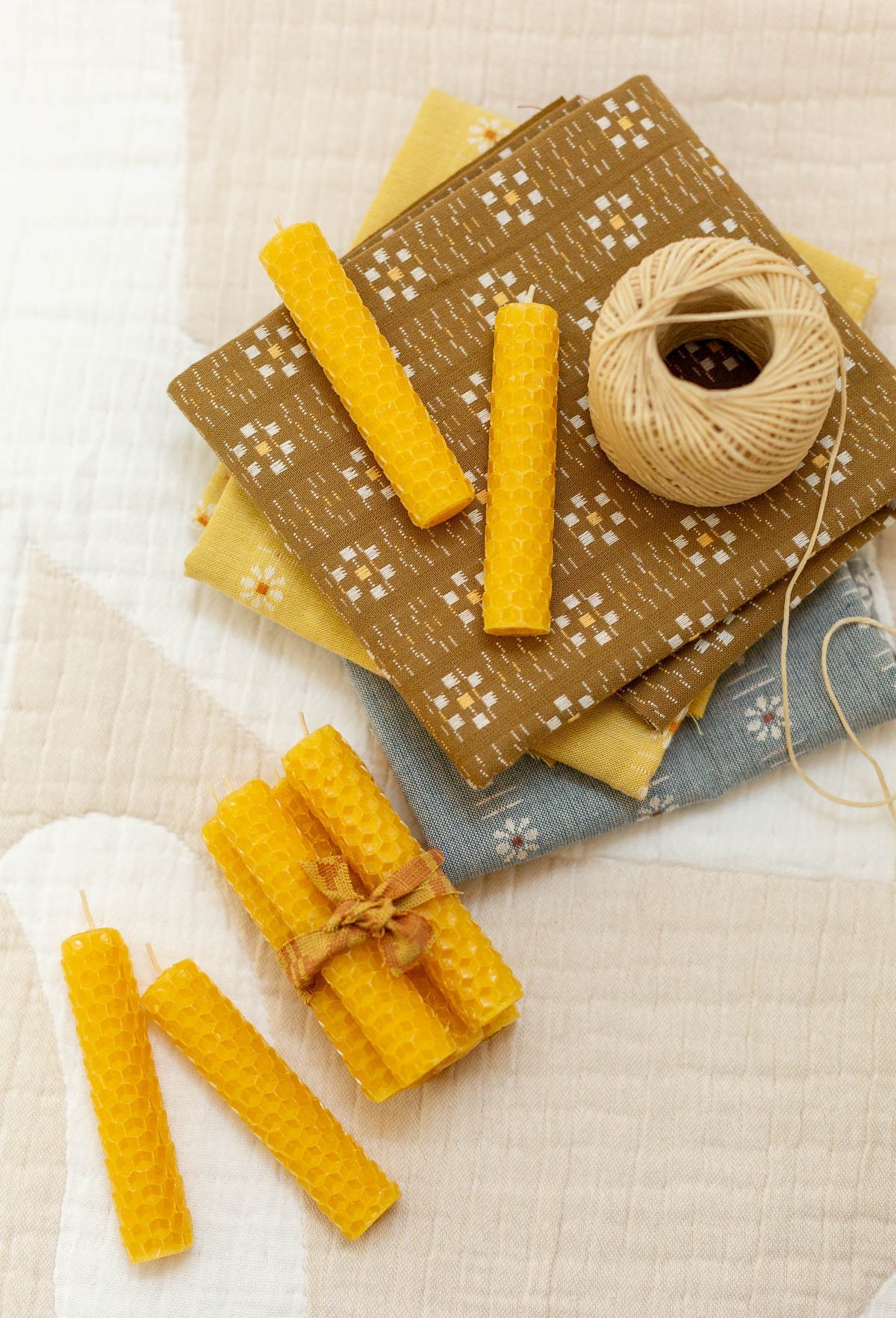 rolled beeswax candles on fabric scraps in a crafting room