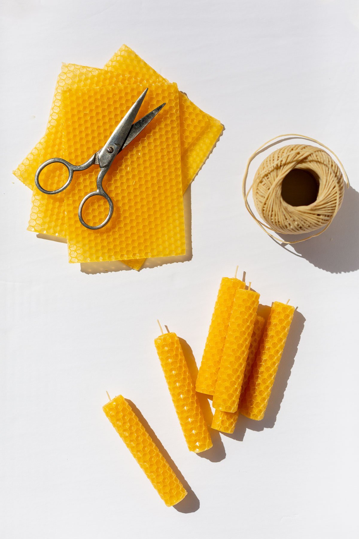 materials for making rolled beeswax candles and completed candles as well, on white background