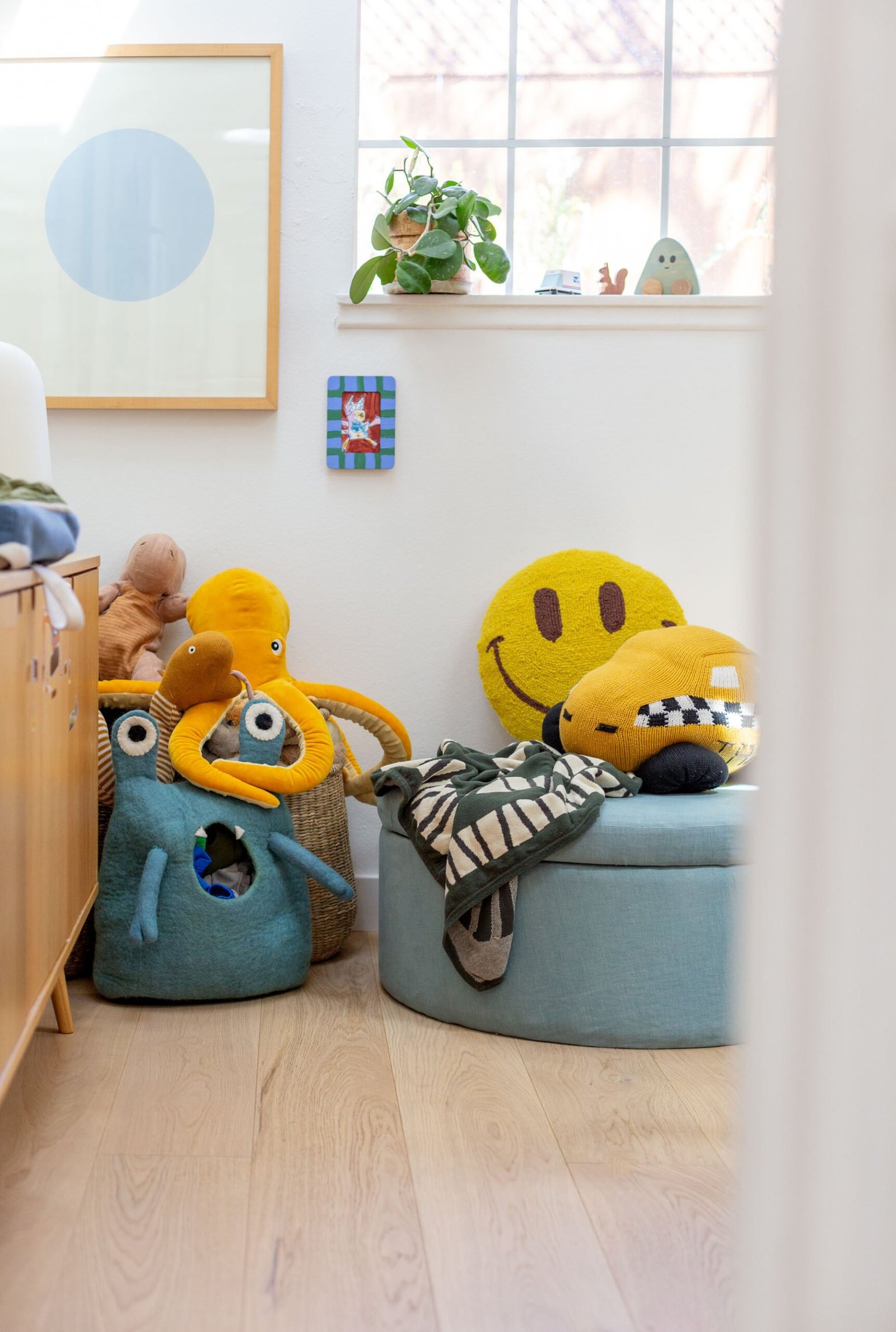 white bright kids room with colorful toys and blue round ottoman