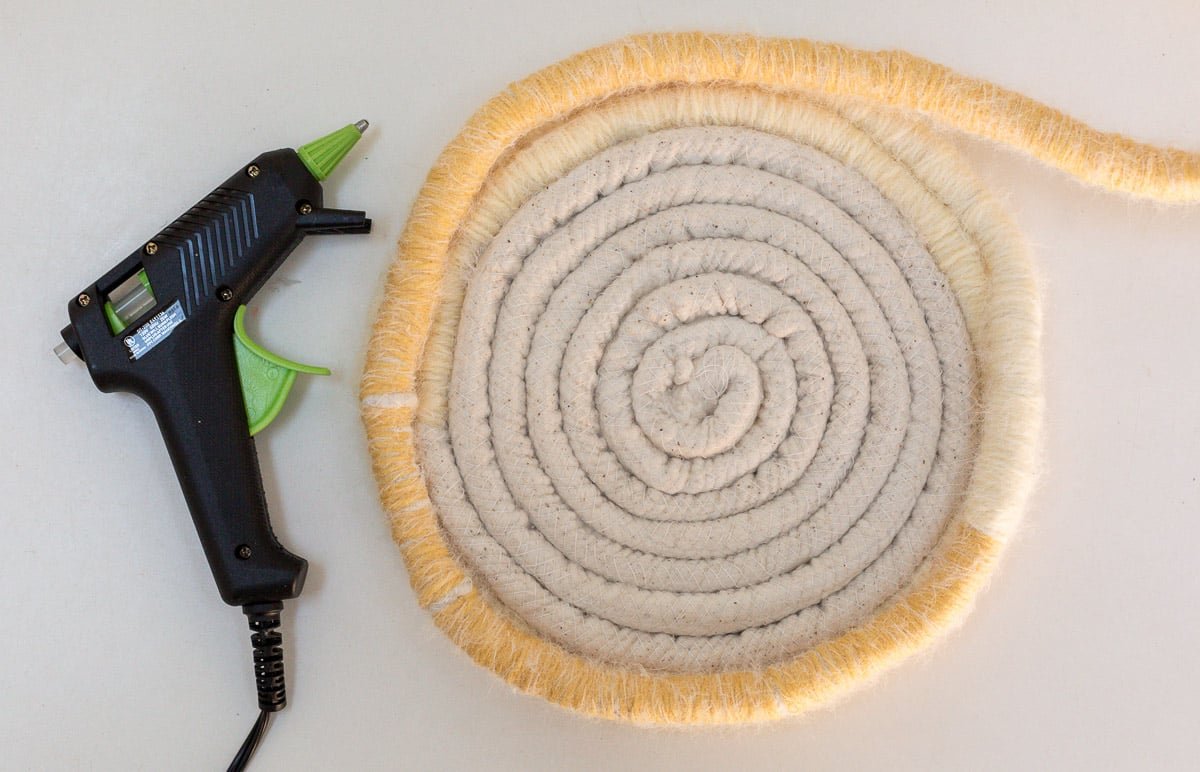 glueing cotton cording together to make a basket, with hot glue