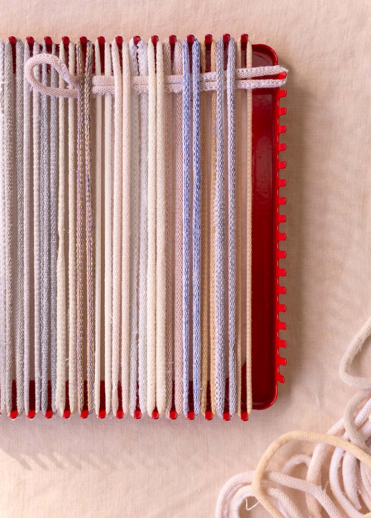 weaving on a potholder loom with neutral cotton loops